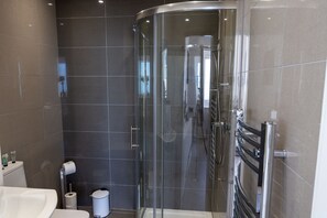 A modern bathroom with a glass shower enclosure, a toilet, and a sink. - The Halcyon (Eastbourne)