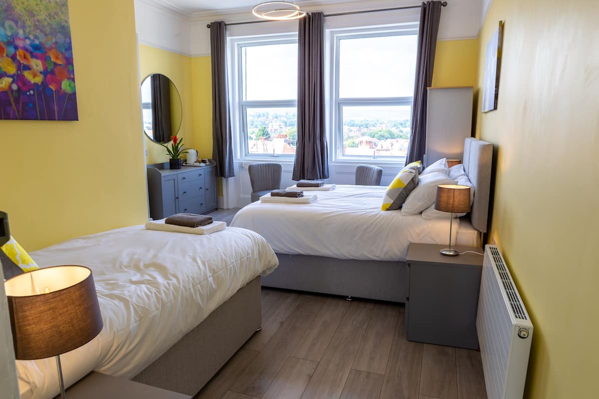 A hotel room with two beds, a dresser, a mirror, and a window with curtains.