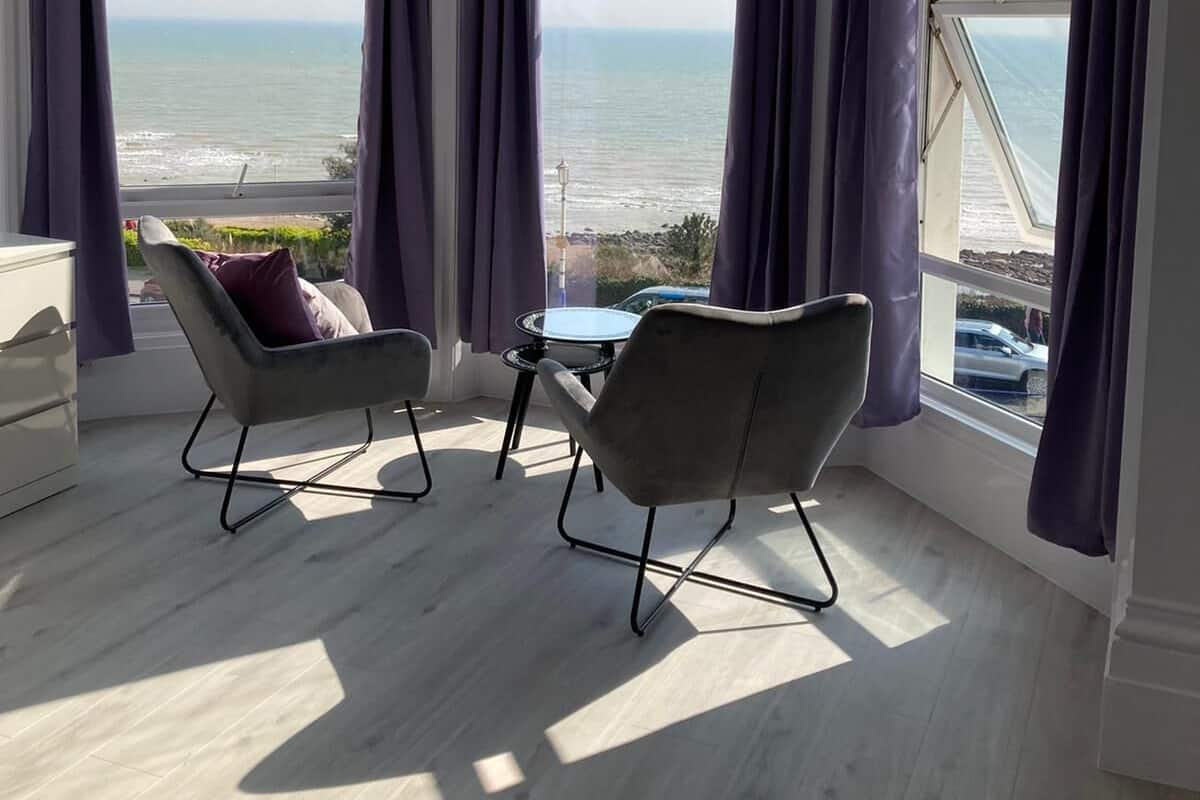 A room with a view of the sea, featuring two chairs and a small table.