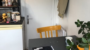 Eine kompakte Küche mit Kühlschrank, einer Kaffeemaschine und einem kleinen Essbereich mit Tisch und Stühlen.