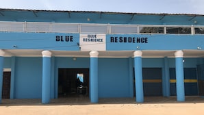 A building with "BLUE RESIDENCE" signage, featuring a covered entrance with columns and a gated driveway. - Blue Residence (Bakau)