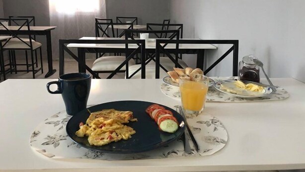 A breakfast table with scrambled eggs, tomatoes, and a glass of orange juice. - Blue Residence (Bakau)