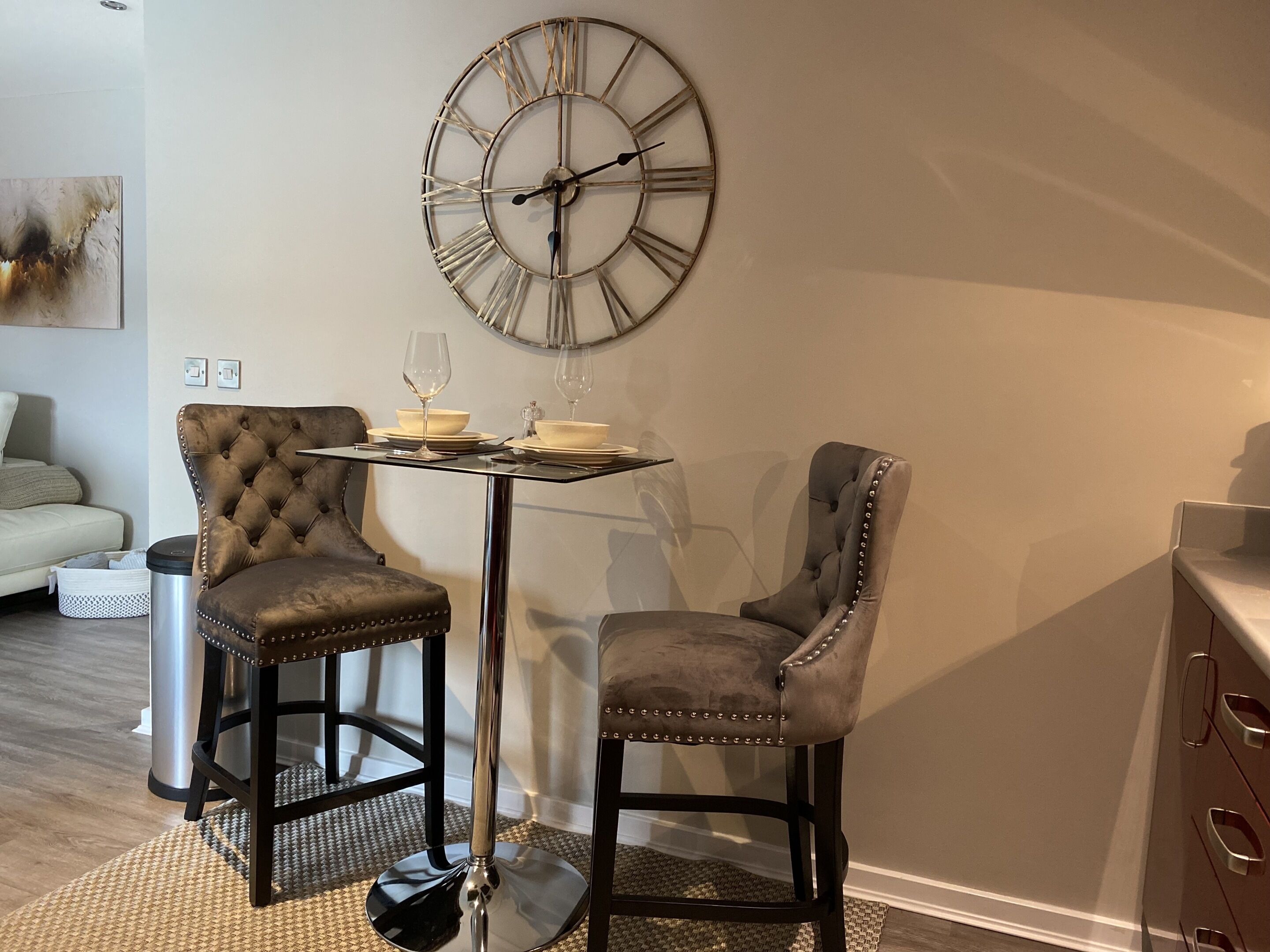 Un rincón comedor con dos sillones capitonados, una mesita y un reloj en la pared.