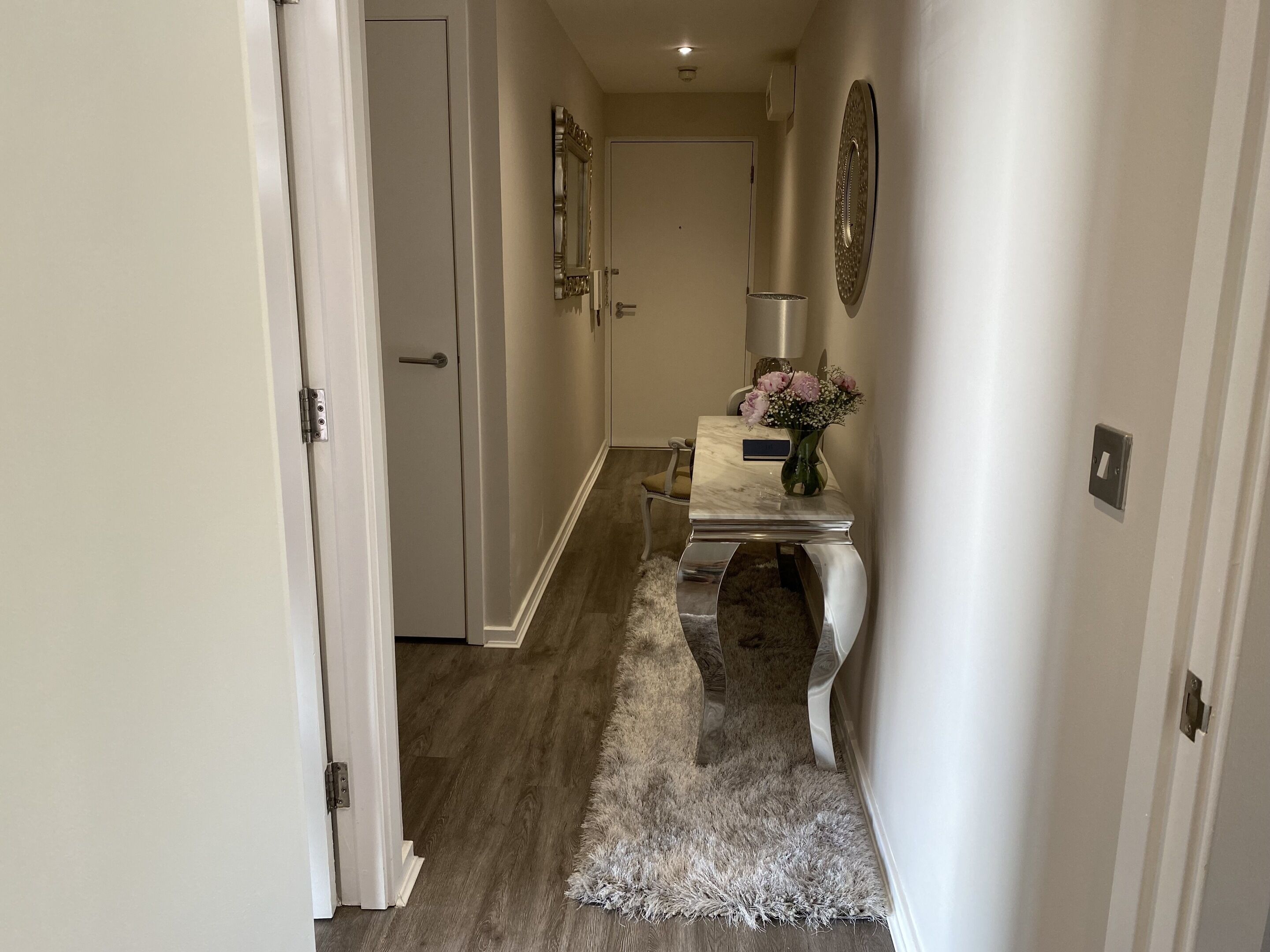 Un couloir avec une table en marbre, un tapis moelleux et une porte donnant sur une autre pièce.