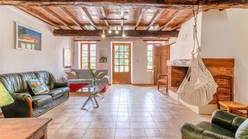 Un salon spacieux doté d’un plafond en bois, d’un canapé en cuir vert, d’une table basse en bois et d’un fauteuil suspendu.