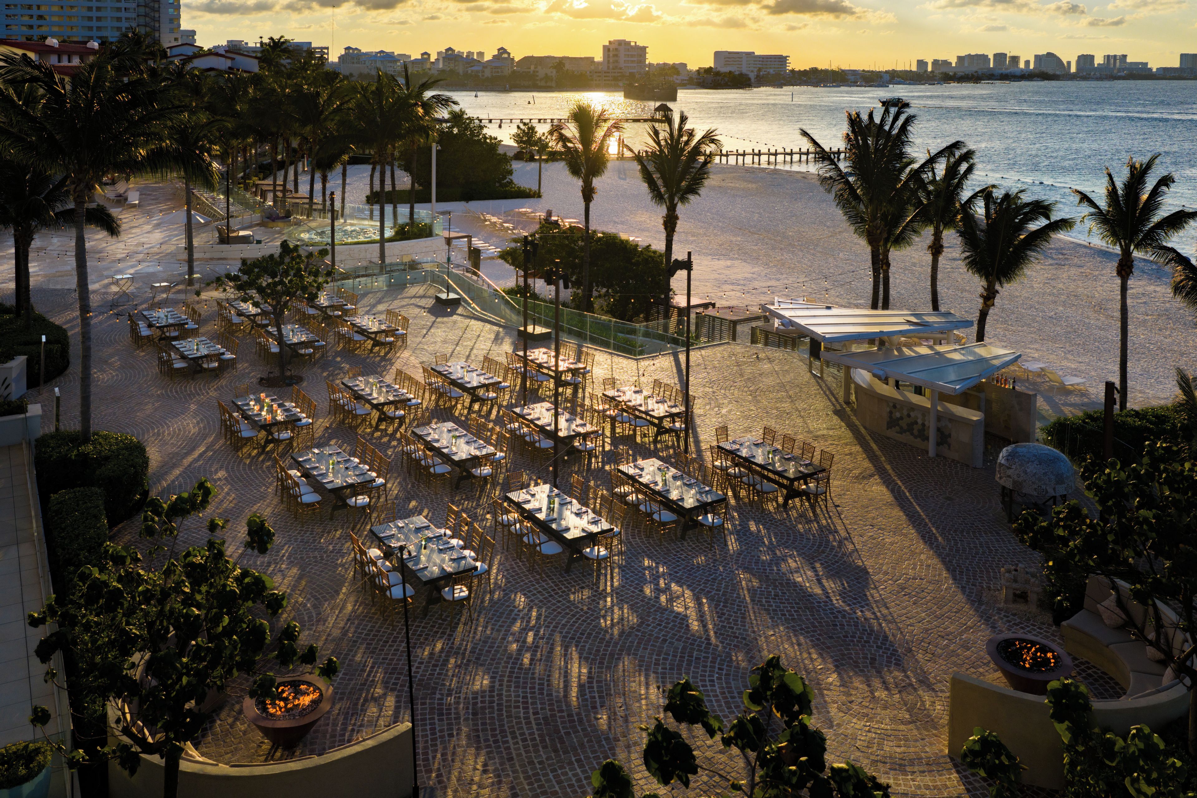 Uma área de refeições no terraço, com mesas e cadeiras, com vista para uma praia e o oceano.