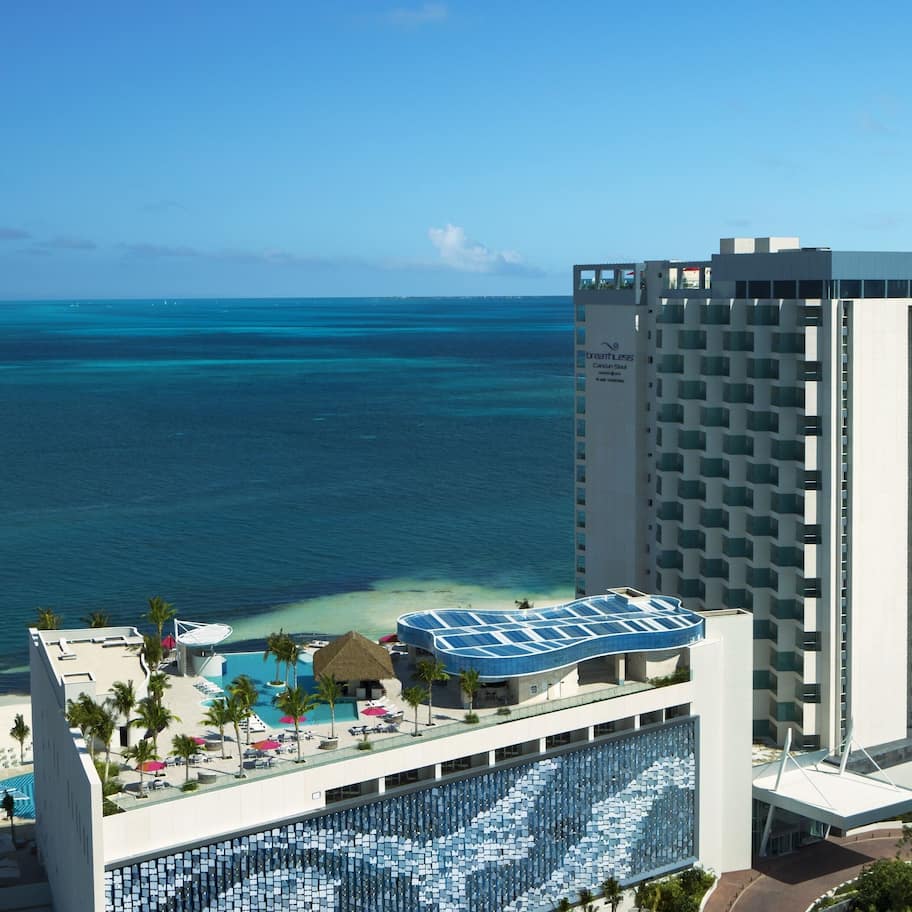A hotel with a large pool area, a beach view, and a high-rise building.