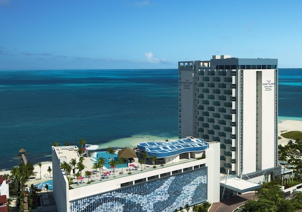 Un hôtel doté d’une grande piscine, offrant une vue sur la plage et comprenant un immeuble de grande hauteur.
