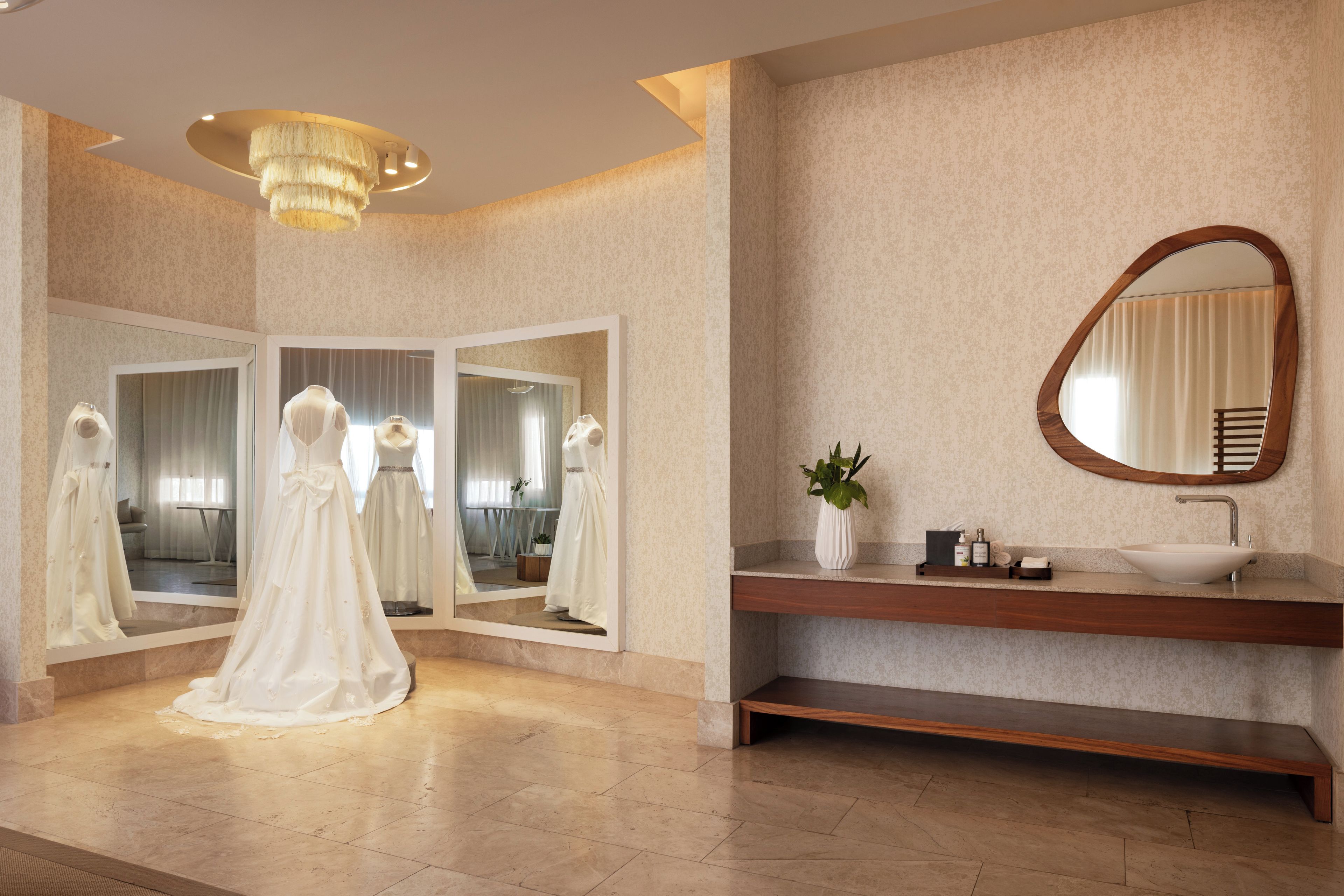 Una habitación con un espejo grande, un tocador con lavabo y un vestido expuesto.