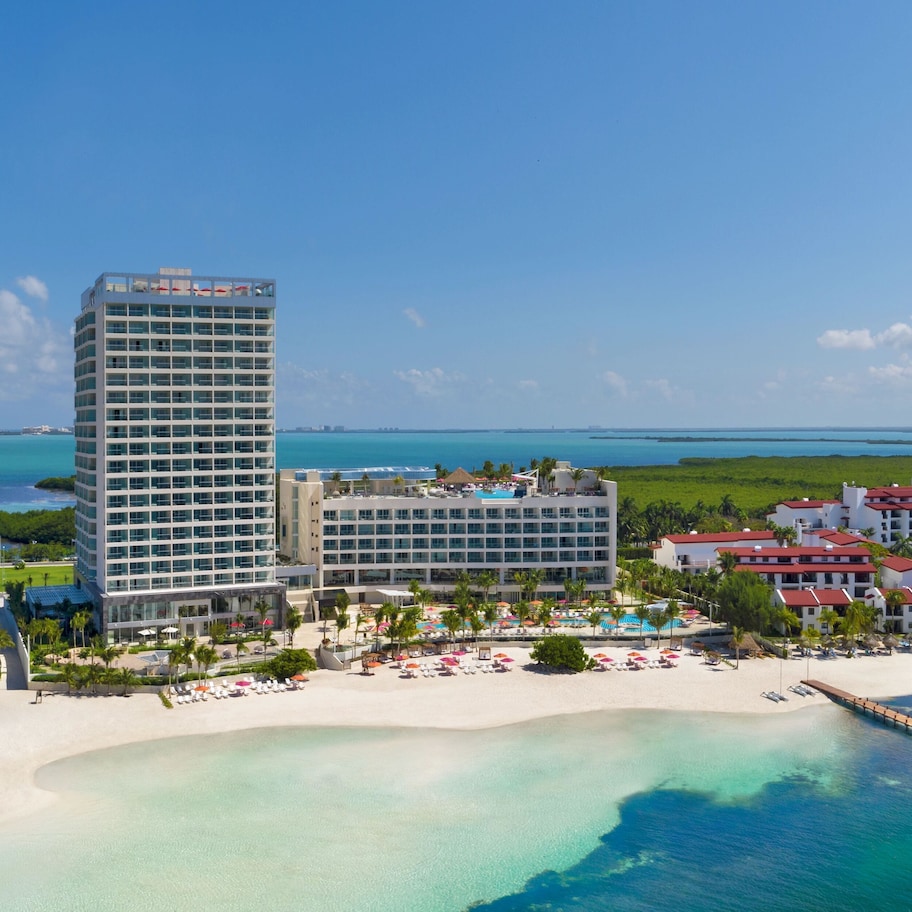 A resort with a large hotel building, a beach, and a pier.