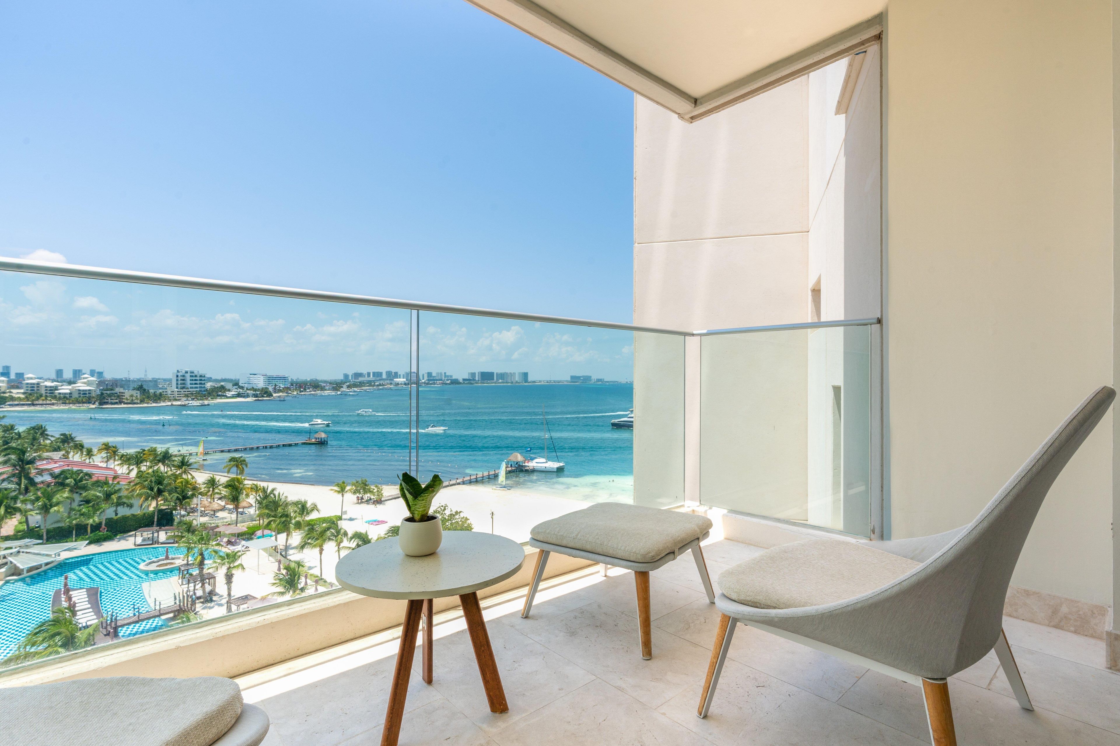 Un balcón con vistas al mar, una piscina y un paisaje urbano.