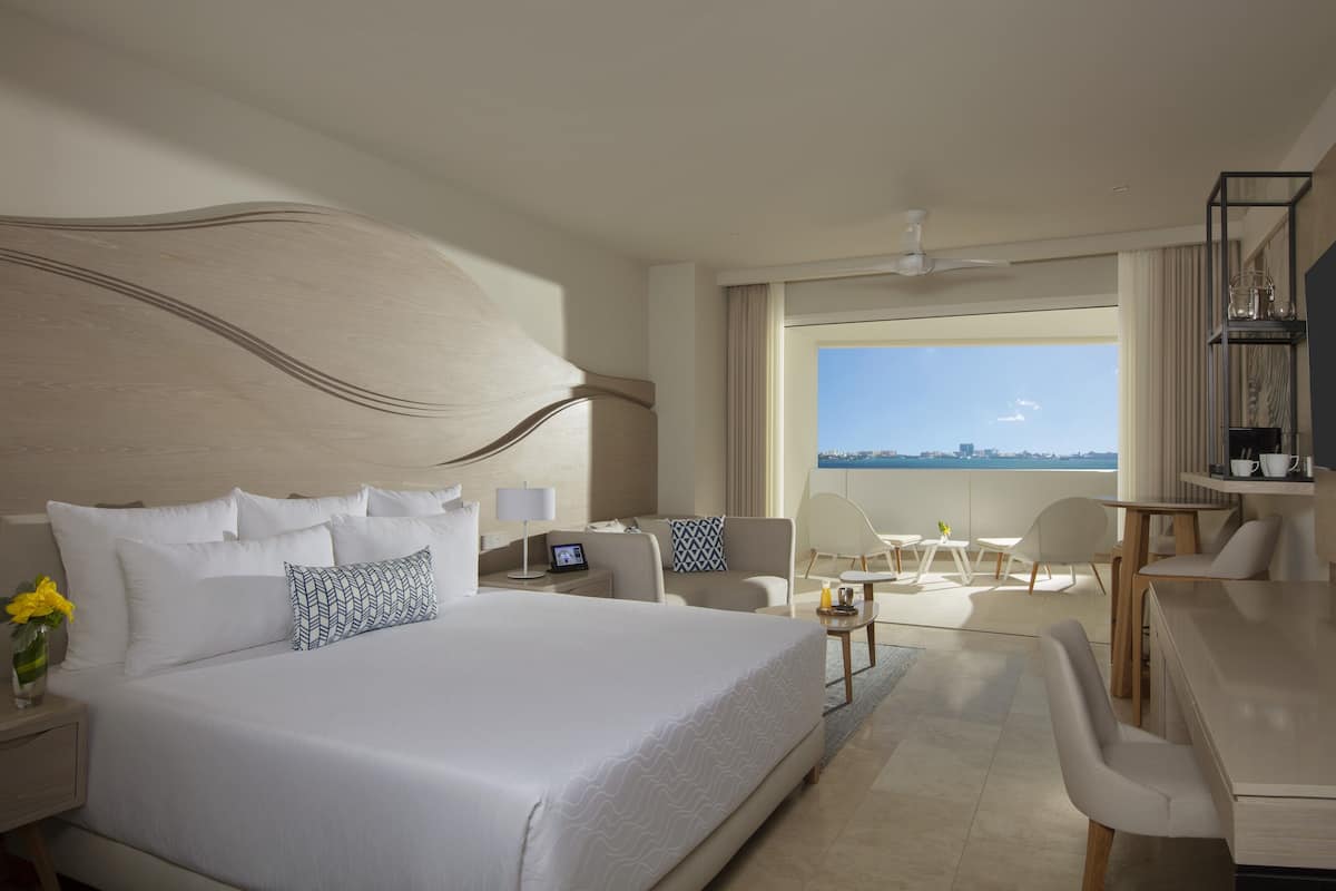 Een hotelkamer met een groot bed, een bureau en een balkon met uitzicht.