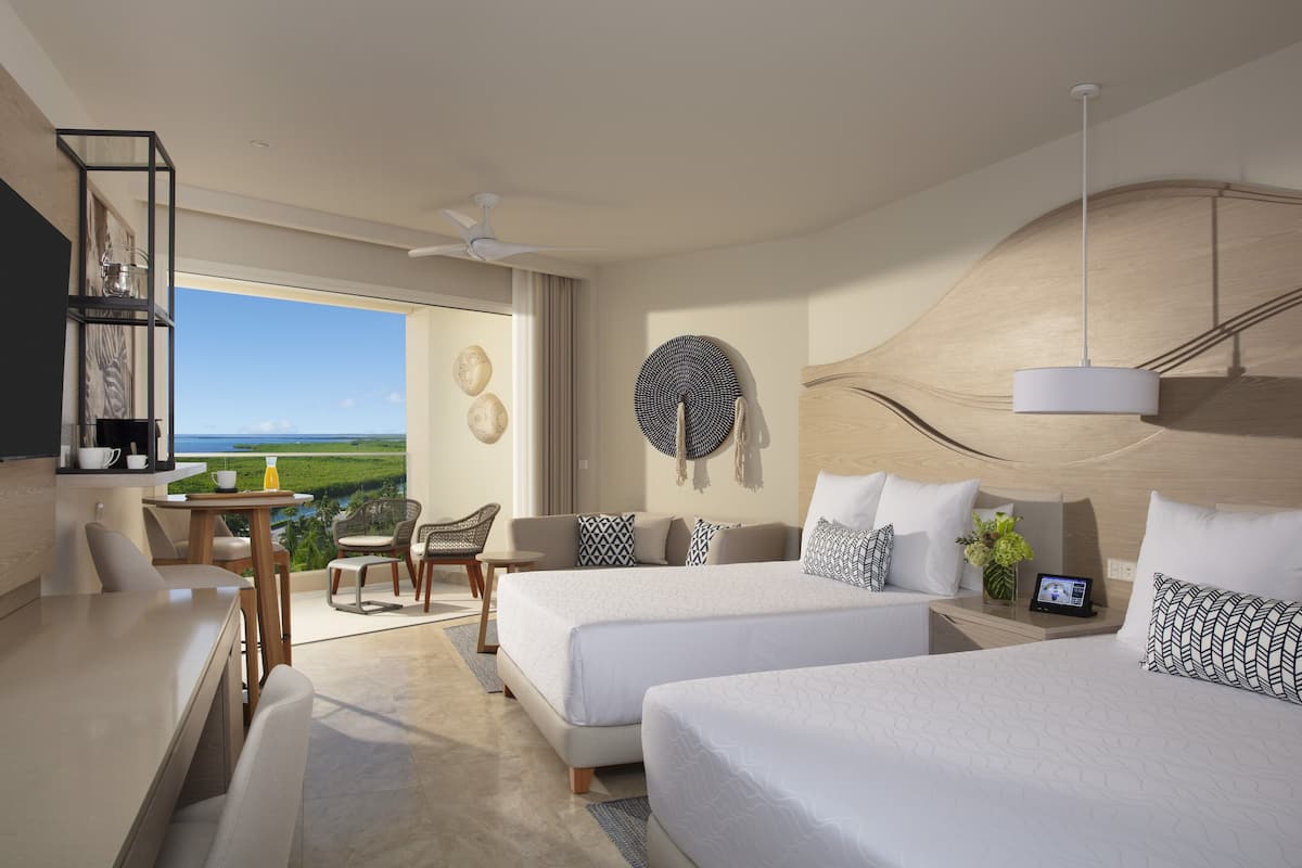 Een moderne hotelkamer met twee bedden, een zithoek en uitzicht op het landschap.