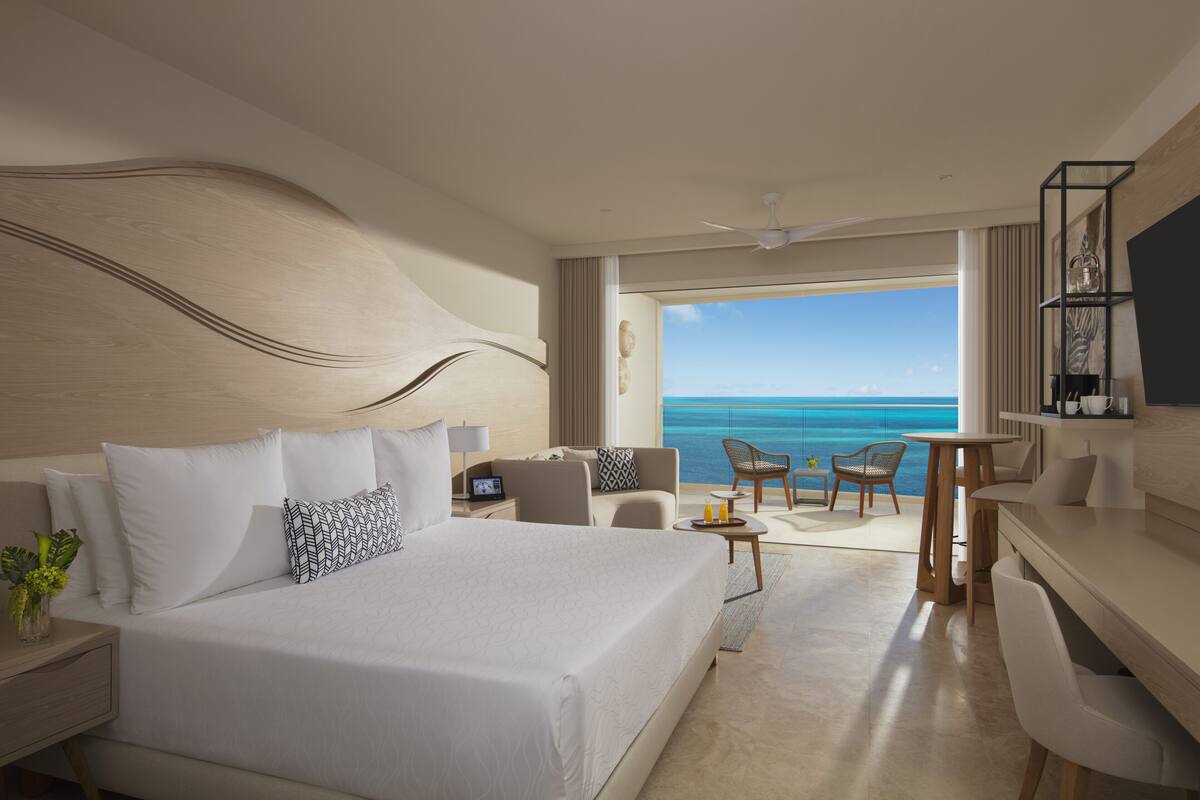 Een moderne hotelkamer met een groot bed, een bureau en uitzicht op zee.