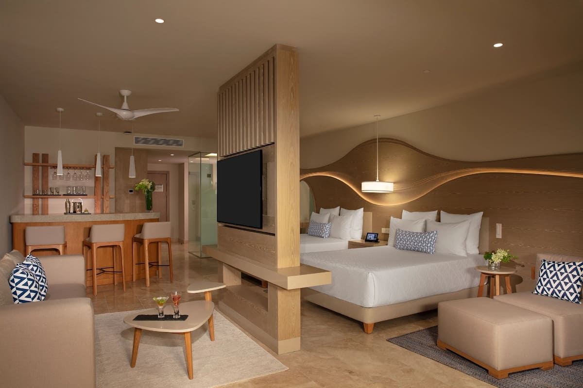Een moderne hotelkamer met een groot bed, een televisie, een bureau en een zithoek.