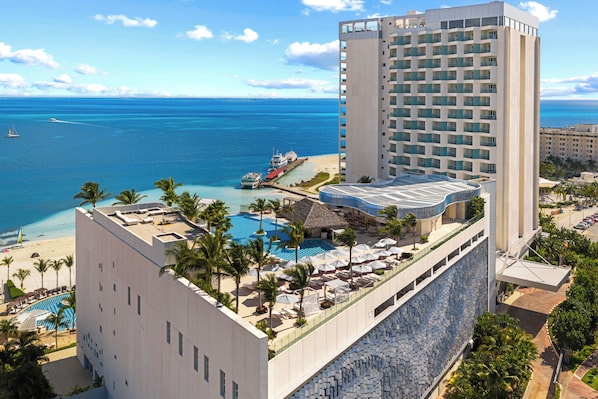 A hotel with a rooftop pool, a beach view, and a large building with balconies.