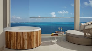 Une salle de bain moderne avec une baignoire en bois, une petite table ronde avec un plateau et un canapé en osier.