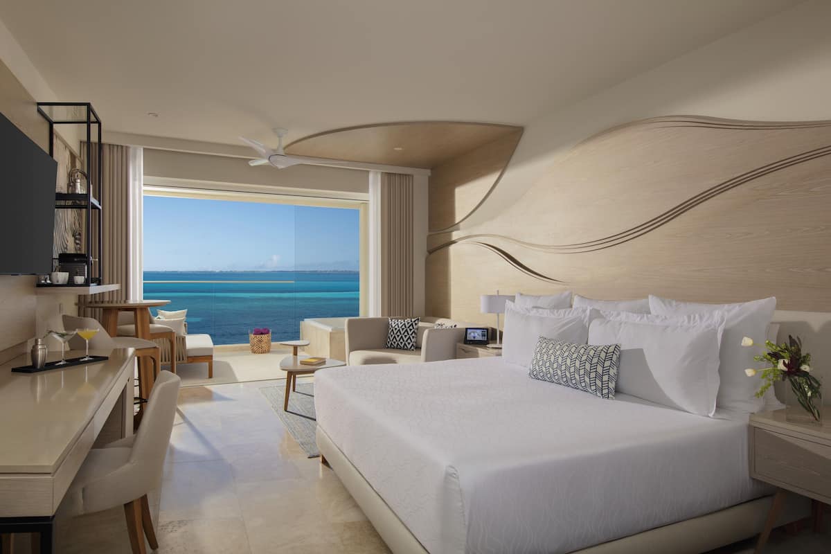 Een moderne hotelkamer met een groot bed, een bureau en uitzicht op de oceaan.
