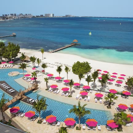 A resort with a large pool, beach area, and ocean view.