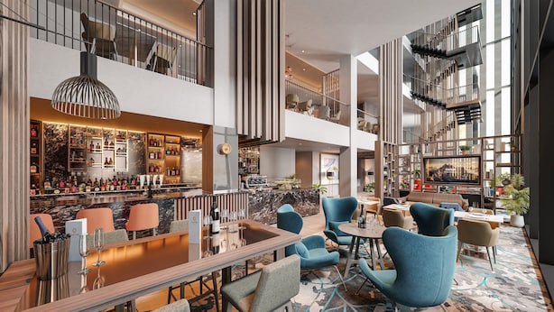 Een moderne hotel lobby met een bar, zitplaatsen en een trap.