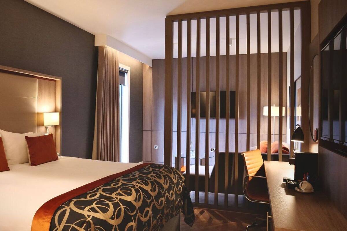 Une chambre d’hôtel avec un grand lit, un bureau et une vue par la fenêtre, qui est dotée de rideaux.
