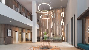 Een moderne hotel lobby met een centrale glazen tafel, een receptiebalie en een zithoek.