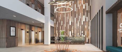 A modern hotel lobby with a central glass table, a reception desk, and a seating area.