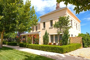 Una casa a due piani con un portico coperto, un muro in pietra e un prato curato.