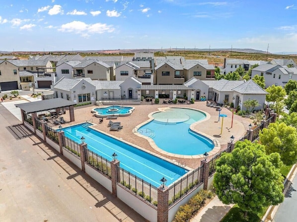 A residential complex with multiple houses, a swimming pool, and a covered patio area. - Spacious Home with Large Kitchen (Hurricane)