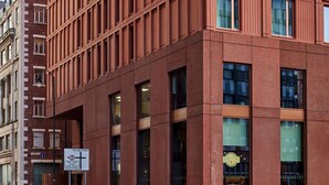 A modern red-brick building with a grid of windows and a sign indicating a restaurant. - Maldron Hotel Manchester City Centre (Manchester)
