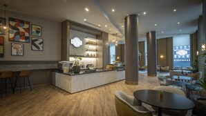 A modern coffee shop with a bar area, seating, and artwork on the walls. - Maldron Hotel Manchester City Centre (Manchester)
