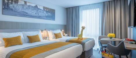 A hotel room with two beds, a desk, a chair, and a giraffe toy.