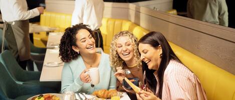 A group of people dining in a restaurant with yellow booths and a casual atmosphere.