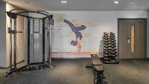 A gym with a wall mural, weight racks, and exercise equipment. - Maldron Hotel Manchester City Centre (Manchester)