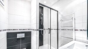 Un baño moderno con ducha envuelta en vidrio, un lavamanos blanco y un inodoro.