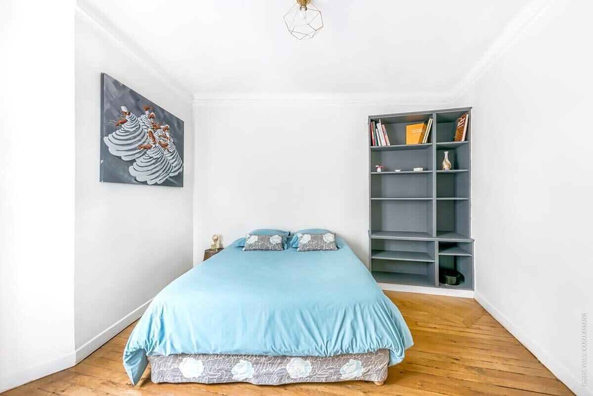 Ein Schlafzimmer mit einem Bett, einem Bücherregal und einem Bild an der Wand.