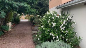 Un sendero de grava que conduce a una casa de fachada color beige y techo de tejas.