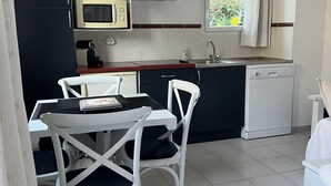 Cocina compacta con comedor, que incluye una mesa con sillas, microondas, cafetera y lavavajillas.