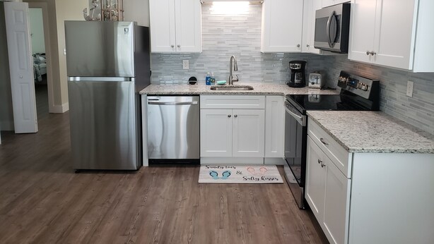 A modern kitchen with white cabinets, stainless steel appliances, and a tiled backsplash.