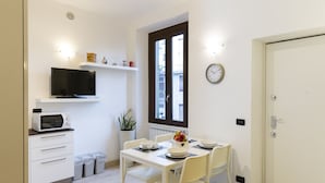 Una cocina compacta con microondas, televisión y una mesa de comedor preparada para cuatro.