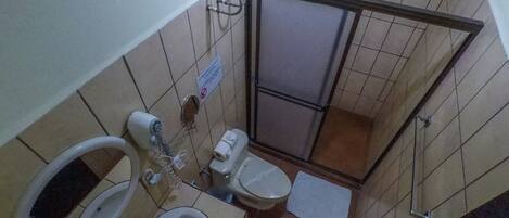 Une petite salle de bain avec des toilettes, un lavabo et une douche.