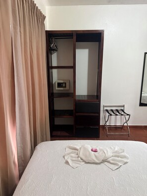 Une chambre d’hôtel avec un lit, une armoire, une petite table et une chaise.