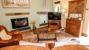 Ein Wohnzimmer mit einer Ledersofa, einem Fernseher, einem Kamin und Holzausbau.