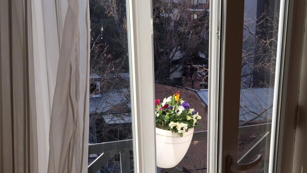 Un balcon avec un pot de fleurs suspendu.