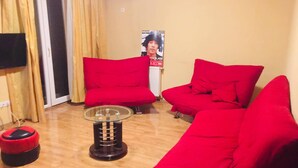 Un salon avec des canapés rouges, une table basse en verre et une affiche accrochée au mur.