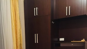 Une chambre à coucher avec un lit, une armoire en bois et un bureau sur lequel est posé un jeu d’échecs.