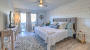 Una camera da letto con un letto, un comodino, una lampada, una sveglia e vista sull'esterno.