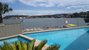 Una piscina con vista su un lago e edifici sullo sfondo.