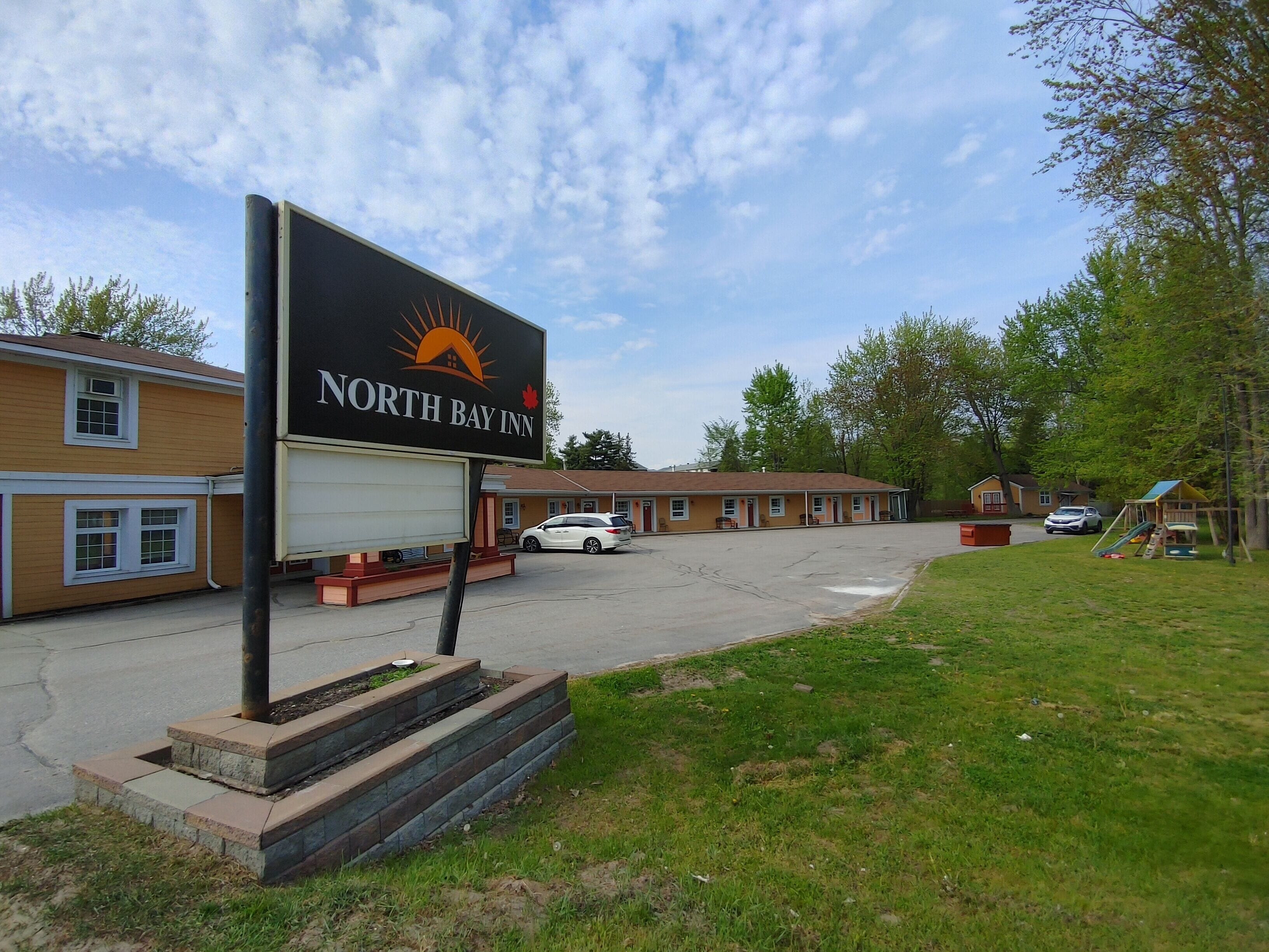 A North Bay Inn with a large sign, a parking lot, and a playground.