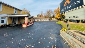 A North Bay Inn with a welcoming sign, a covered parking area, and a row of motel-style buildings. - North Bay Inn (North Bay)